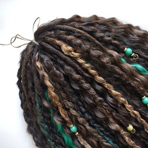 May include: Brown and blonde synthetic dreadlocks with green accents and beads. The dreadlocks are tied together at the top.