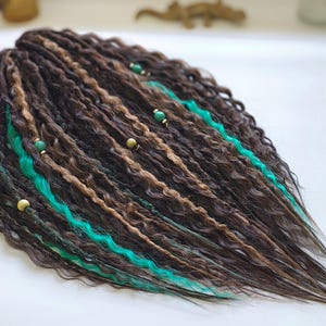 May include: Brown and blonde synthetic dreadlocks with turquoise accents and gold beads. The dreadlocks are wavy and long.