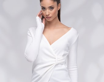 May include: A white long-sleeved shirt with a twist detail at the front, paired with black skinny jeans and black ankle boots.