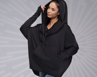 Peut inclure: Un sweat à capuche noir surdimensionné avec un cordon de serrage et une grande poche sur le devant. Le mannequin porte un jean bleu et des bottines noires.