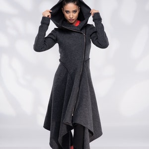 May include: A grey hooded asymmetrical long coat with a zip closure. The model is wearing red boots.