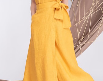 May include: A yellow linen dress with a wrap skirt and a tie at the waist. The dress has short sleeves and a round neckline.