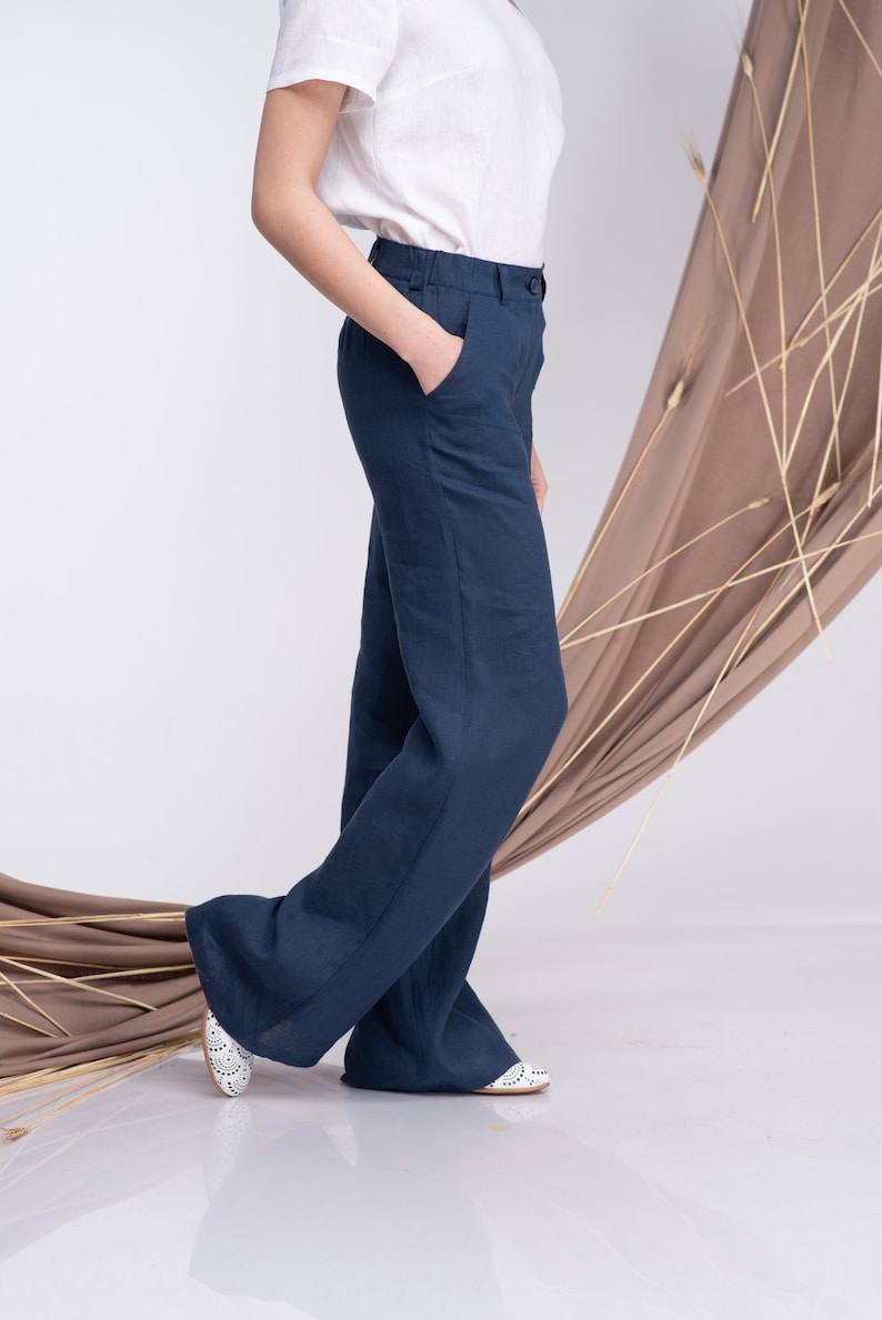 May include: A pair of wide-leg, dark blue linen trousers. The trousers have a straight leg and a high waist.
