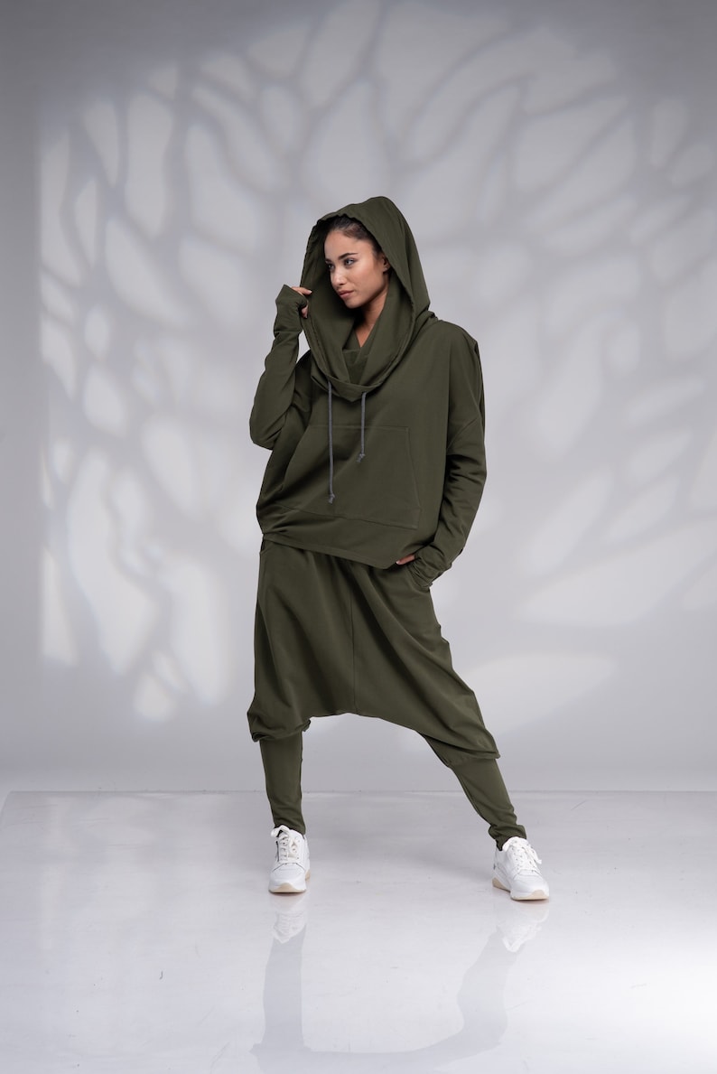 Puede incluir: Una sudadera con capucha verde y pantalones a juego con cord&oacute;n. La sudadera tiene una capucha grande y ca&iacute;da y un bolsillo canguro. Los pantalones son holgados y tienen una pierna ancha.