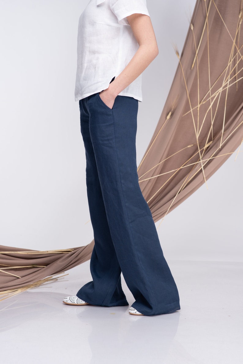 May include: A pair of wide-leg, dark blue linen trousers. The trousers have a relaxed fit and are made from a lightweight, breathable fabric.