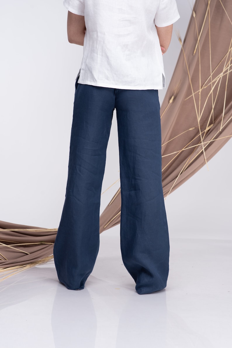 May include: A pair of wide-leg, dark blue linen trousers. The trousers have a relaxed fit and a straight leg.