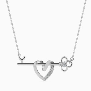 May include: Silver necklace with a key pendant featuring a heart design with small diamonds. The key has a decorative keyhole and a small diamond in the center.