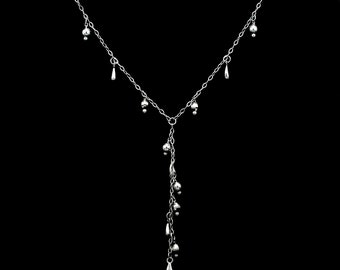 May include: A silver necklace with a long, dangling chain of small silver beads and teardrop-shaped charms.
