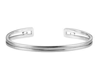May include: A silver cuff bracelet with a minimalist design. The bracelet has a double-banded structure with a smooth, polished finish. The open ends feature rectangular cutouts, adding a modern touch to the jewellery.