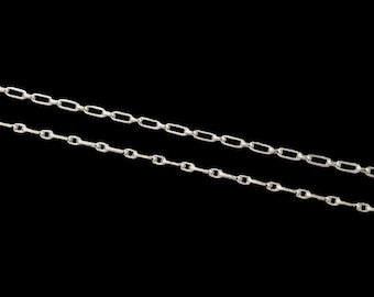 May include: Two silver chains with a box link design. The chains are laying on a black background.