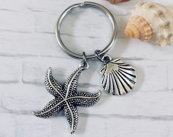 May include: Silver key chain with a starfish and seashell charm. The charms are attached to a silver key ring.
