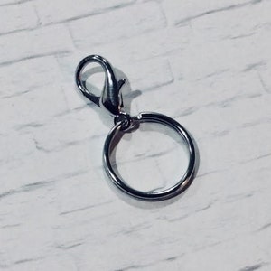 以下が含まれることがあります： 回転式留め具と丸いリングが付いたシルバーのキーチェーン