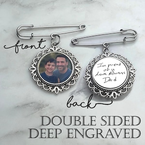 May include: Double-sided, deep-engraved brooch with a photo of a man and a boy on the front. The back of the brooch has handwritten text that reads "I'm proud of u Love Always Dad". The brooch is attached to a silver safety pin.