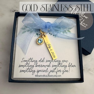 Op de afbeelding: Een gouden roestvrijstalen hanger met een blauwe edelsteen en een label met de inscriptie "July 4, 2026" hangt aan een blauw lint. De hanger wordt gepresenteerd in een marineblauwe doos met de tekst "Something old, something new..." en "WillowAndBlueJewelry.etsy.com".