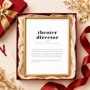 May include: A gold-framed print inside a red gift box with white tissue paper. The text reads: theatre director, noun, resourceful, creative, collaborative. The definition describes a visionary holding together actors, egos, and set pieces.