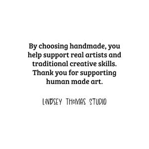 Pode incluir: Fundo branco com texto preto. O texto diz: "Ao escolher feito &agrave; m&atilde;o, voc&ecirc; ajuda a apoiar artistas reais e habilidades criativas tradicionais. Obrigado por apoiar a arte feita pelo homem. LINDSEY THOMAS STUDIO."