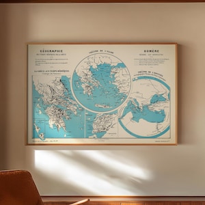 May include: A framed vintage map of Greece, featuring detailed cartography in blue and white, hangs on a wall. The map is in a wooden frame. A mid-century modern style chair with a brown leather seat and wooden frame sits in front of the map.