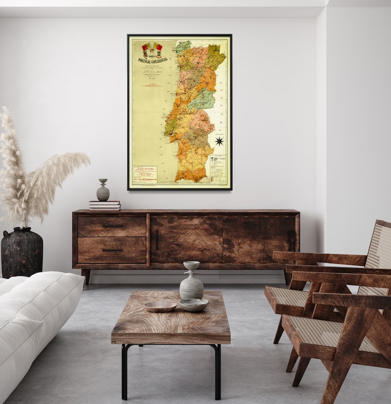 Puede incluir: Un mapa vintage de Portugal en un marco negro, colgado en una pared blanca sobre un aparador de madera. El mapa est&aacute; en tonos de amarillo, verde y marr&oacute;n, con un escudo rojo y amarillo en la parte superior. El mapa est&aacute; titulado "Portugal Continental" y muestra las diferentes provincias de Portugal.