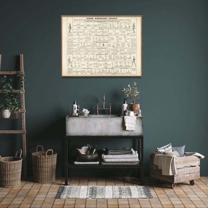 May include: A vintage-style home exercise chart in a wooden frame hangs on a teal wall above a bathroom sink with a concrete countertop. The chart features illustrations of various exercises with descriptions. The bathroom has a rustic aesthetic with a wooden ladder, wicker baskets, and a wooden crate.