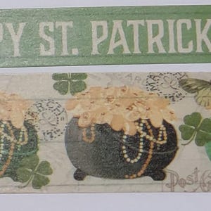 May include: Decorative washi tape with a St. Patrick's Day theme. The design features pots of gold, shamrocks, and butterflies. The top banner reads "HAPPY ST. PATRICK'S DAY" in white letters on a green background.