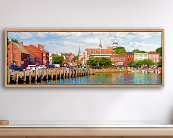 May include: A panoramic landscape painting in a light wood frame depicting a waterfront town with red brick buildings, a wooden pier extending into blue water, and a clear sky. The artwork is displayed on a white wall above a wooden counter.