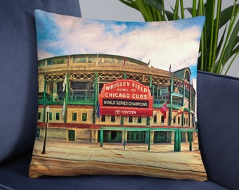 May include: A decorative pillow featuring an artistic rendering of Wrigley Field, home of the Chicago Cubs. The image includes the stadium's exterior, with the text "WRIGLEY FIELD HOME OF CHICAGO CUBS WORLD SERIES CHAMPIONS" on a red sign. The pillow is on a blue surface.
