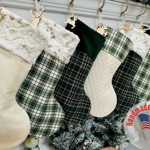 May include: Set of six Christmas stockings with a patchwork design. The stockings are made from a variety of fabrics, including plaid, velvet, and faux fur. The stockings are decorated with wooden reindeer ornaments and the text "Handmade in the USA".