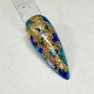 May include: A close-up of a long, pointed, blue and gold nail with a metallic finish. The nail is decorated with gold flakes and blue and green glitter.