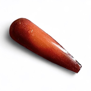 May include: A long, tapered, reddish-brown object with a glossy finish. The object has a rounded top and a pointed tip. The color transitions from a darker shade at the top to a lighter, shimmering hue towards the middle.