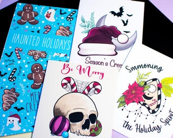 Puede incluir: Una colección de tarjetas de felicitación con temática navideña. Una tarjeta presenta un fondo azul con hombres de jengibre y el texto "Haunted Holidays". Otras tarjetas muestran una calavera, murciélagos y un gorro de Papá Noel con el texto "Season's Cree."