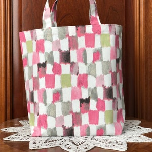 May include: A small pink, green, and gray checkered tote bag with fabric handles.