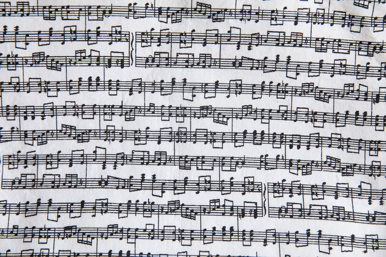 Puede incluir: Primer plano de una tela blanca cubierta de notaci&oacute;n musical negra. La partitura presenta pentagramas, notas y otros s&iacute;mbolos musicales. El patr&oacute;n se repite en la tela, creando un efecto texturizado.