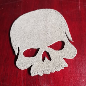May include: A white leather skull patch with a stitched edge.