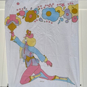May include: A white fabric wall hanging with a colorful illustration of a person in a blue and purple outfit holding a golden object. The background features a row of colorful flowers and stars.