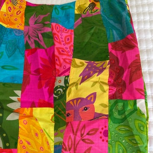 Può includere: Una gonna patchwork colorata con una varietà di stampe floreali e animali. La gonna è realizzata con diversi tessuti cuciti insieme in uno stile patchwork. La gonna è un mix vibrante di rosa, verde, giallo e blu.