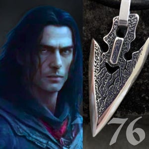 May include: A silver-toned arrowhead pendant featuring a textured, dark recessed surface with intricate, jagged patterns. The pendant is suspended from a black cord and is displayed next to a digital illustration of a dark-haired character.