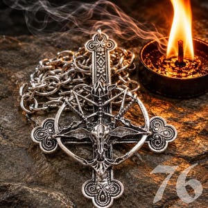 Könnte beinhalten: Ein silberfarbener Metallanhänger mit einem Kreuzdesign und einem komplexen Ziegenschädel-Motiv, das in einem kreisförmigen Rahmen zentriert ist. Der Anhänger ist an einer dicken silbernen Gliederkette befestigt und weist detaillierte Prägemuster auf.