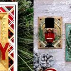 Op de afbeelding: Vier kerstkaarten met een notenkraker in een rood, groen en blauw uniform. De kaarten zijn versierd met gouden randen en een feestelijk ruitpatroon. Op één kaart staat het woord "VREUGDE".