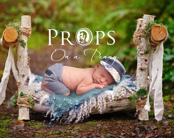 May include: A newborn baby is sleeping on a rustic wooden bed made of branches and moss. The bed is decorated with a white fabric and a blue blanket. The baby is wearing a gray outfit and a plaid hat. The text "PROPS On a Penny" is visible in the background.