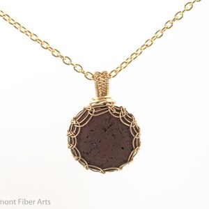 May include: A gold chain necklace with a brown lava rock pendant wrapped in gold wire.