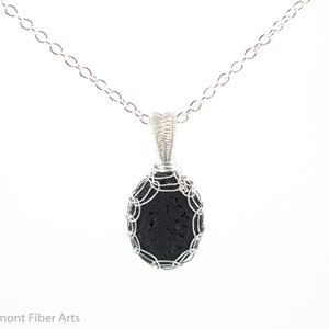 May include: A silver chain necklace with a black lava rock pendant wrapped in silver wire.
