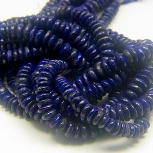May include: A strand of dark blue lapis lazuli beads, each bead is a flat, oval shape with a slightly rounded edge.