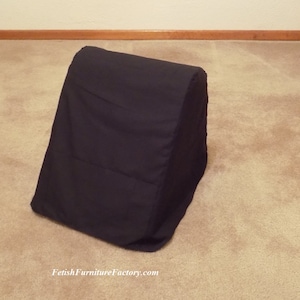 Puede incluir: Una almohada negra en forma de cuña con un diseño acolchado. La almohada está hecha de una tela oscura y suave y está colocada sobre una alfombra de color neutro. El producto es de FetishFurnitureFactory.com.