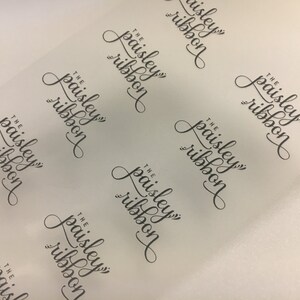 K&ouml;nnte beinhalten: Ein Blatt aus klarem, halbtransparenten Papier mit dem Text "The Paisley Ribbon", der sich in einem Muster wiederholt.