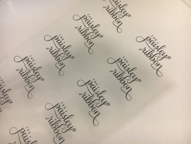 K&ouml;nnte beinhalten: Ein Blatt aus klarem, halbtransparenten Papier mit dem Text "The Paisley Ribbon", der sich in einem Muster wiederholt.