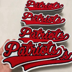 Puede incluir: Un montón de parches bordados rojos y blancos con la palabra "Patriots" en una fuente de escritura. Los parches tienen un borde blanco y un contorno azul marino.