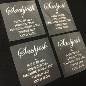K&ouml;nnte beinhalten: Vier transparente Kleidungsetiketten mit dem Markennamen "Sachjosh" in wei&szlig; gedruckt. Jedes Etikett zeigt eine andere Gr&ouml;&szlig;e an: S, M, L und XL. Die Etiketten enthalten auch Pflegehinweise: "Made in USA", "100&nbsp;% Baumwolle", "Maschinenw&auml;sche kalt", "Trocknen im W&auml;schetrockner", und "Kalt b&uuml;geln".