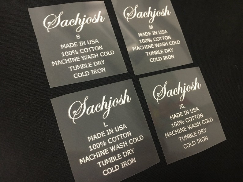 K&ouml;nnte beinhalten: Vier transparente Kleidungsetiketten mit dem Markennamen "Sachjosh" in wei&szlig; gedruckt. Jedes Etikett zeigt eine andere Gr&ouml;&szlig;e an: S, M, L und XL. Die Etiketten enthalten auch Pflegehinweise: "Made in USA", "100&nbsp;% Baumwolle", "Maschinenw&auml;sche kalt", "Trocknen im W&auml;schetrockner", und "Kalt b&uuml;geln".