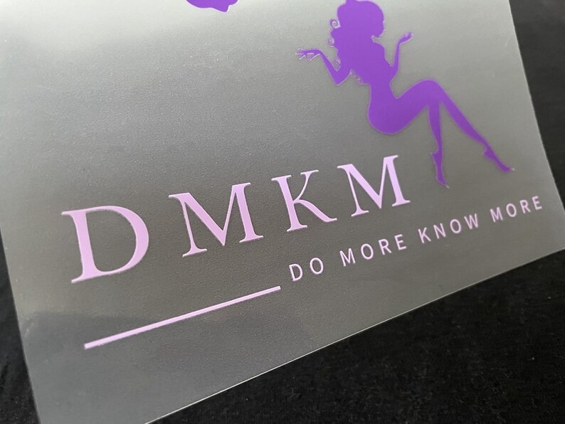 K&ouml;nnte beinhalten: Lilafarbene Silhouette einer sitzenden Frau mit dem Text "DMKM DO MORE KNOW MORE" in wei&szlig;en Buchstaben auf hellgrauem Hintergrund.