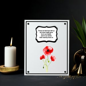 Op de afbeelding: Een ingelijste print met een witte achtergrond, zwarte rand en vier zwarte hoekaccenten. De print toont een aquarel illustratie van rode klaprozen en een tekst die luidt: "Degenen die we hebben verlaten zijn nooit echt weg, want in onze harten en in onze gedachten leeft hun herinnering voort."